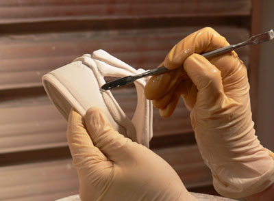 Martha Grover cleans up a pot with a metal tool.