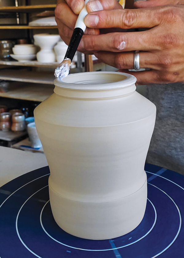 1 Wax the foot of a yunomi using a brush and banding wheel.