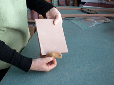 Clean up the edges of the bone dry tile with a sponge to ensure that there are no sharp edges. Then add a base coat of terra sigillata.