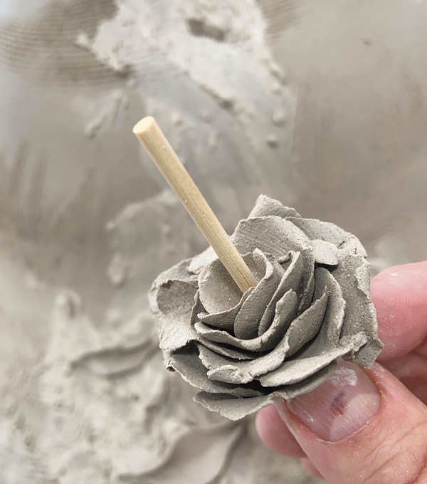 2 To make roses, squeeze clay paper thin between fingers, then layer and overlap around a wooden skewer.