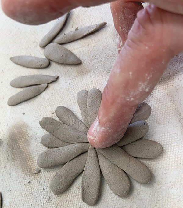 3 For daisies, roll tiny balls, then squeeze to flatten into teardrop shapes and arrange around a center, usually in layers.