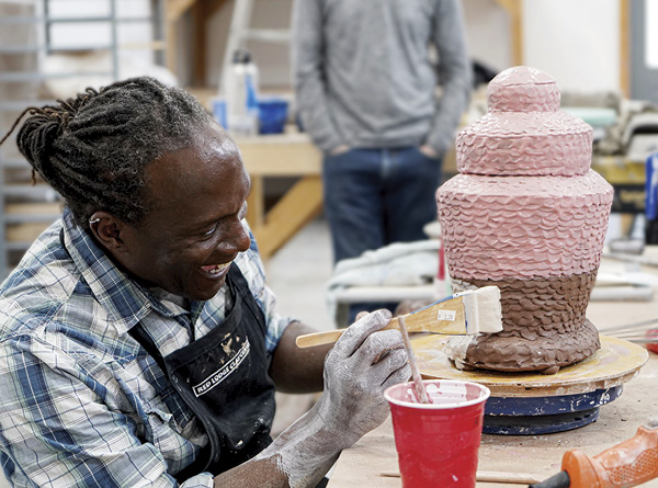 1 Sam Harvey adding slip to a finished piece as part of an AIA (Artist-Invite-Artists) residency at Red Lodge Clay Center in June 2023. Photo: Nathan Goddard. Residency venue: Red Lodge Clay Center, Red Lodge, Montana.