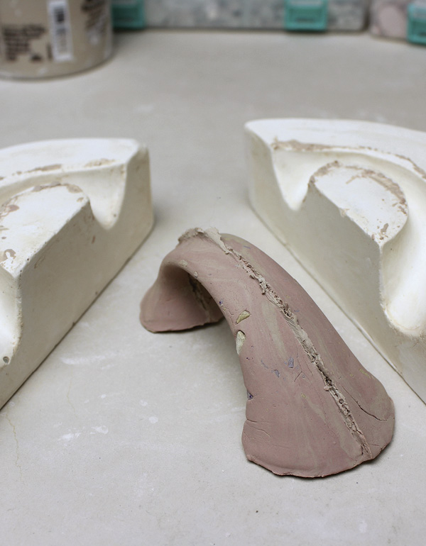 6 Press a coil of marbled clay, rolled in bits, into a plaster handle press mold.