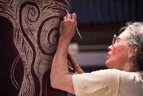 Sandy getting started on the sgraffito for an octopus pot. The black slip-glaze turns shiny in the firing and the exposed clay turns a warm varied brown, as it is fired in reduction.