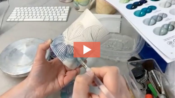 Image of Kirsty Kash painting ceramic underglaze on a carved mug